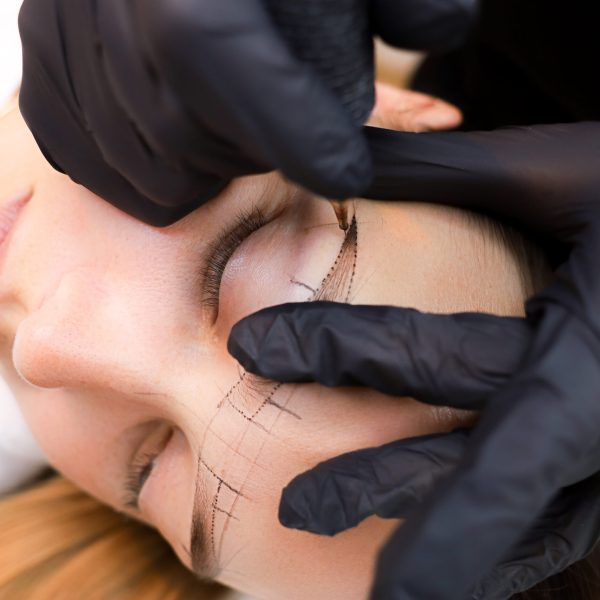 the permanent makeup artist stretches the skin in the area of the eyebrows to perform the tattoo